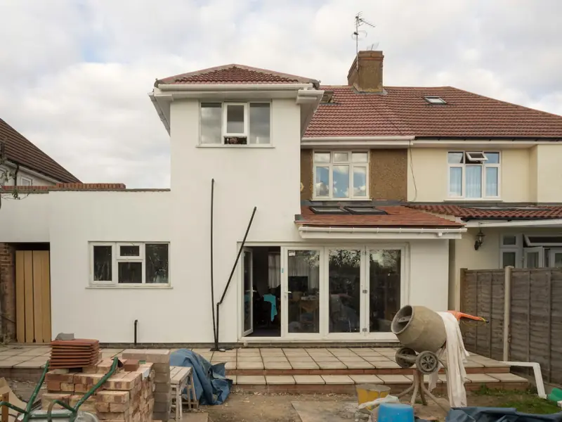 Rear extension under construction with a cement mixer, stacked bricks and new patio doors